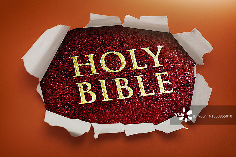 圣经的封面和标题透过撕开的锯齿边缘的纸洞露出来，背景是深橙色图片素材