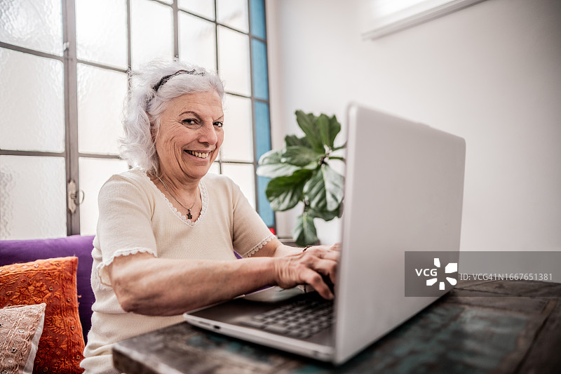 一位老年妇女在家使用笔记本电脑的画像图片素材