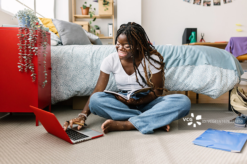 年轻的非裔美国女学生手持笔记本电脑上网。z代黑人女性在线学习，在线看虚拟校园网站。教育与青年理念。图片素材