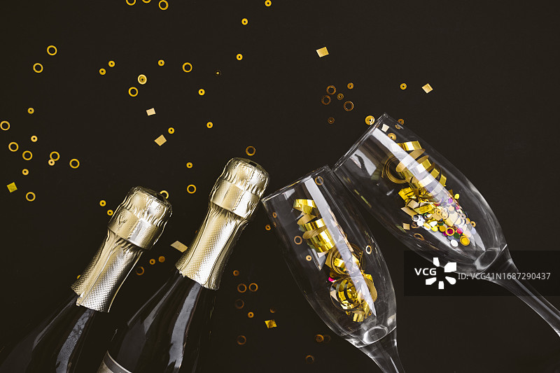 金色的五彩纸屑、香槟酒瓶和黑色背景的玻璃杯图片素材