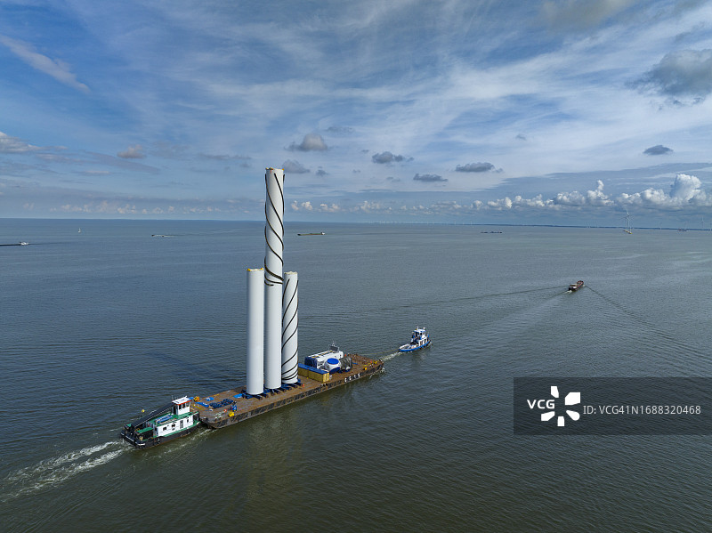 风力涡轮机部件用船运到海上风力发电园区的建筑工地图片素材