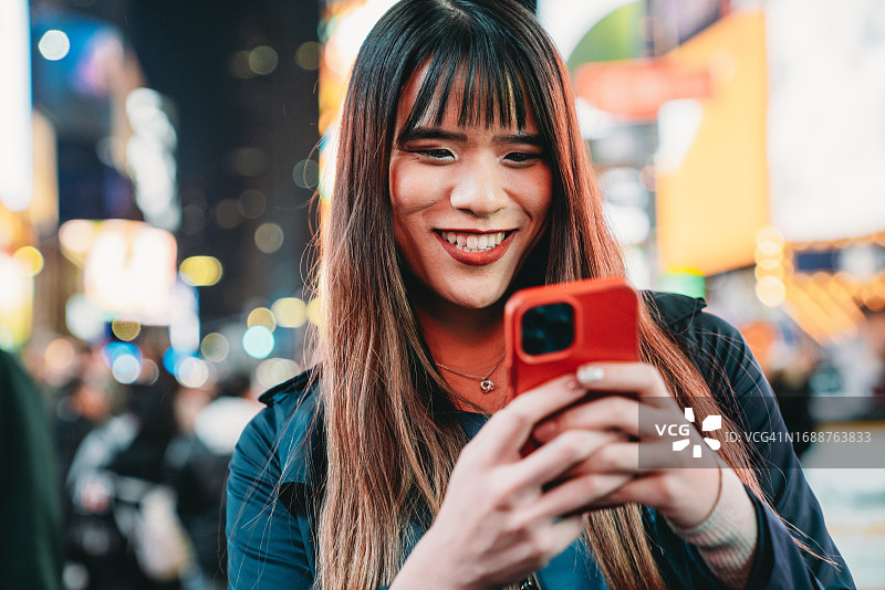 在纽约时代广场，一名亚洲女性正在用智能手机发短信图片素材