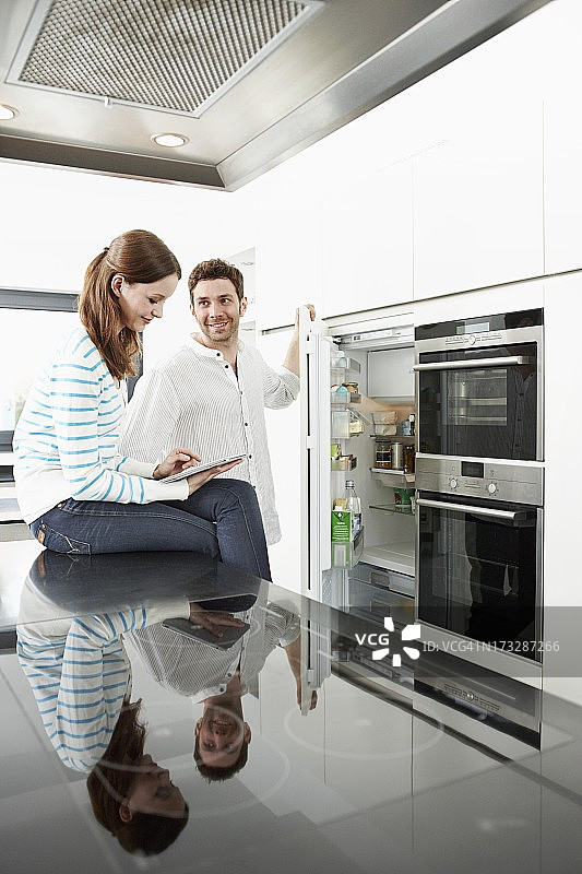 年轻夫妇在厨房里，女人在用平板电脑图片素材