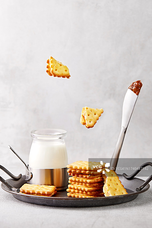 把饼干和牛奶堆在金属托盘上，用焦糖覆盖的刀图片素材