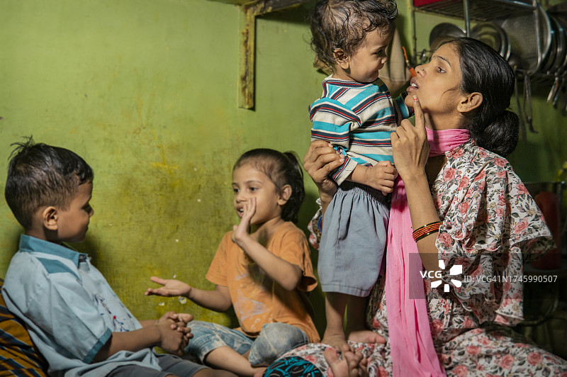 幸福的印度农村孕妇和她的三个孩子在家里的室内肖像。图片素材