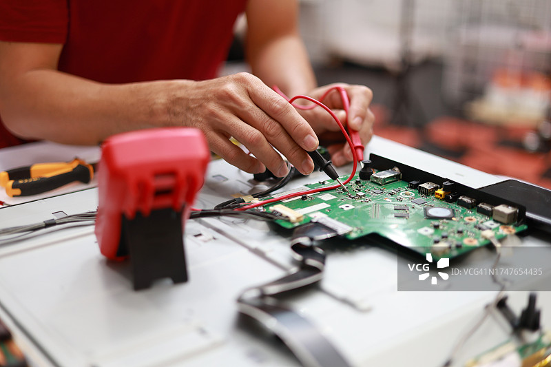 一名亚洲中年男性工程师在他的车间测量导体板上的电压图片素材