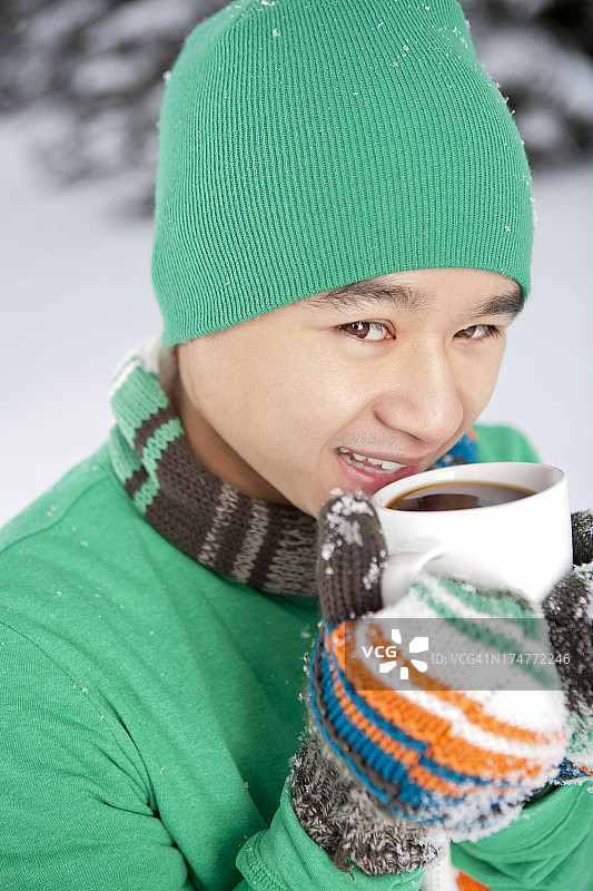 冬日微笑的亚洲男人，端着一杯咖啡图片素材