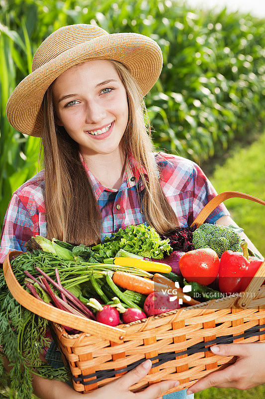 健康年轻的农民女孩抱着篮子的新鲜农产品特写图片素材