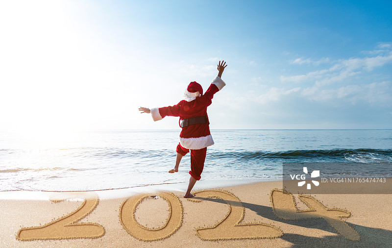 圣诞老人在海滩上兴奋地跳舞，新年的数字是2024图片素材
