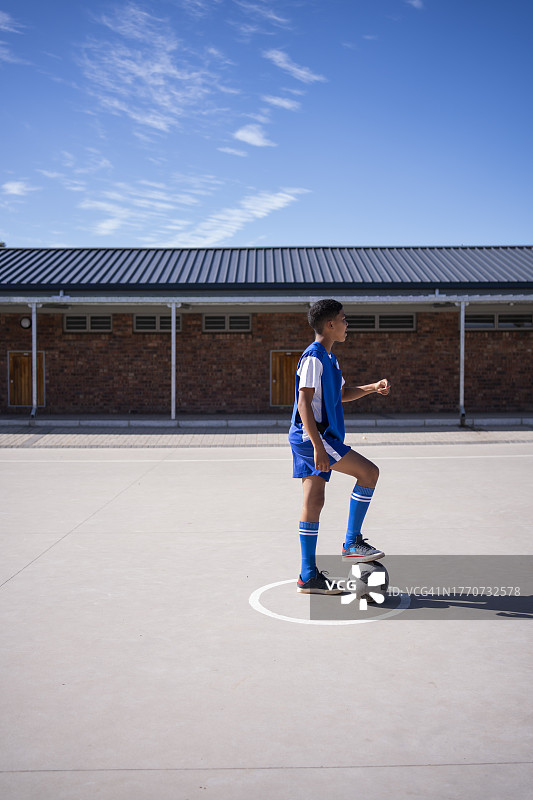 男孩足球运动员在学校的足球场上拿着球图片素材