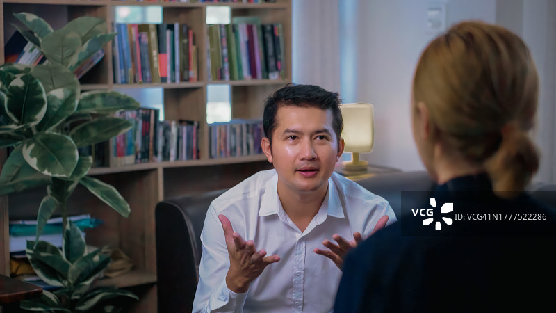 一名亚洲男子在办公室与心理治疗师交谈。图片素材
