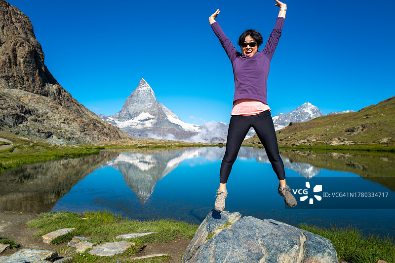 瑞士旅行——一位老年妇女高兴地跳起来，在里弗尔塞附近的瑞士阿尔卑斯山徒步旅行图片素材