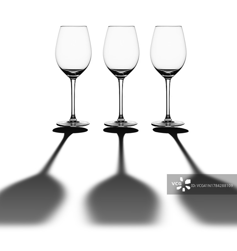 三个空酒杯在白色的背景上有一个长长的影子。图片素材
