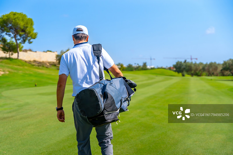 高尔夫球手在高尔夫球场中背着高尔夫球袋行走图片素材