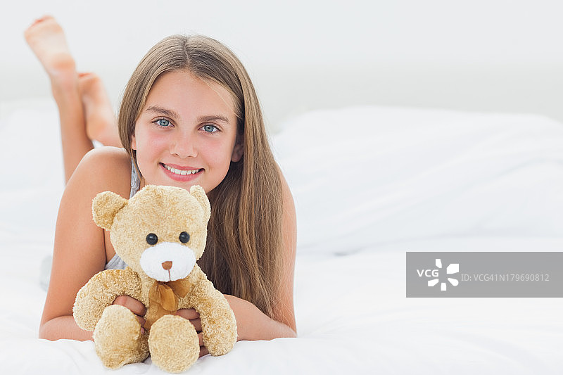 快乐的女孩抱着一只泰迪熊图片素材