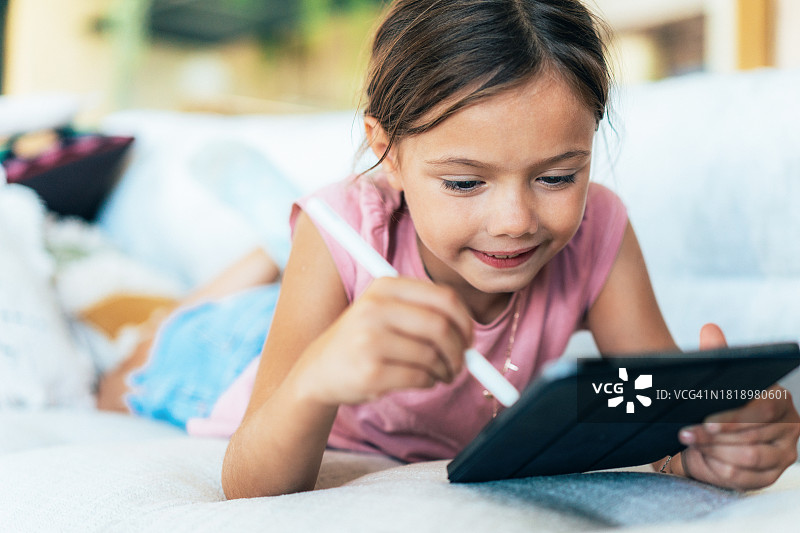 一个小女孩在家里使用数码平板电脑的照片图片素材
