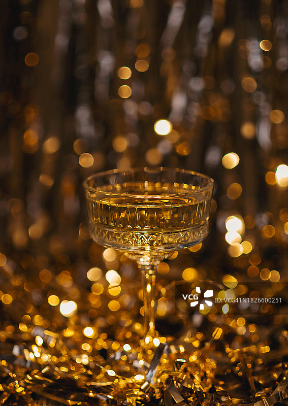 新年贺卡。配有圣诞装饰、彩灯和五彩纸屑的香槟酒杯图片素材
