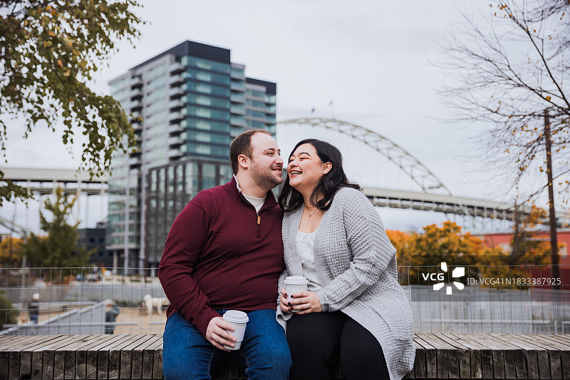 快乐的年轻多种族夫妇在俄勒冈州波特兰市中心喝咖啡约会图片素材