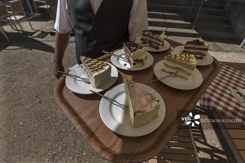 德国巴伐利亚，女服务员端着托盘上的各种蛋糕给客人图片素材