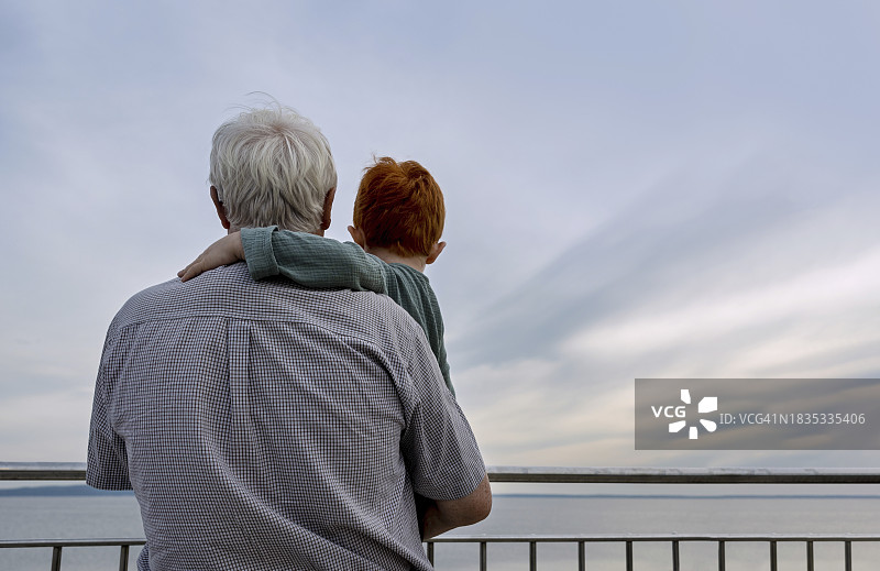 爷爷抱着孙子在天空下的栏杆旁图片素材