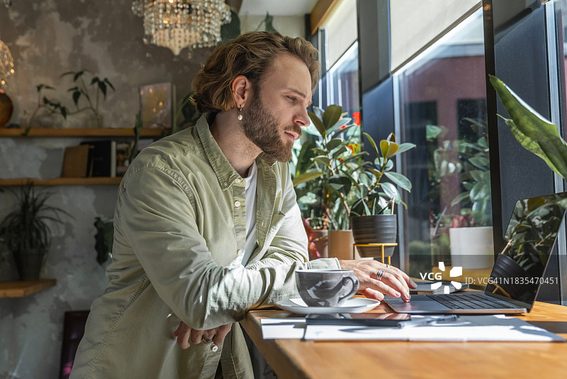 年轻的商人在咖啡馆用笔记本电脑工作图片素材