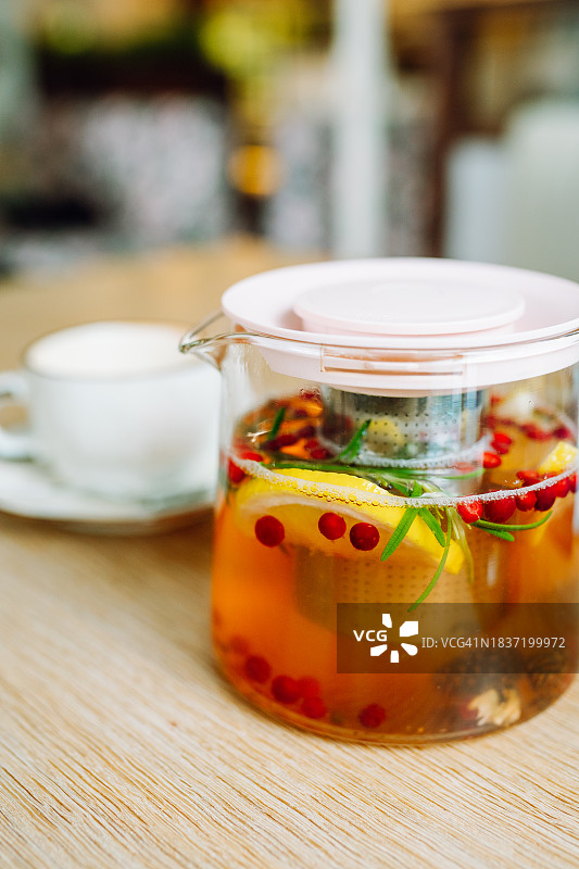 免疫支持。咖啡馆的桌子上，茶壶里放着热草药浆果茶和柠檬图片素材