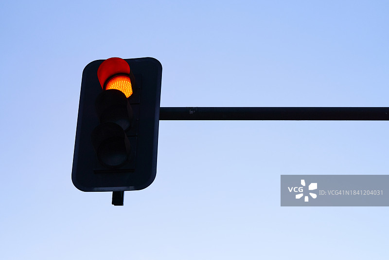 街道上的金属交通灯的低角度视图，背景是红灯和天空图片素材