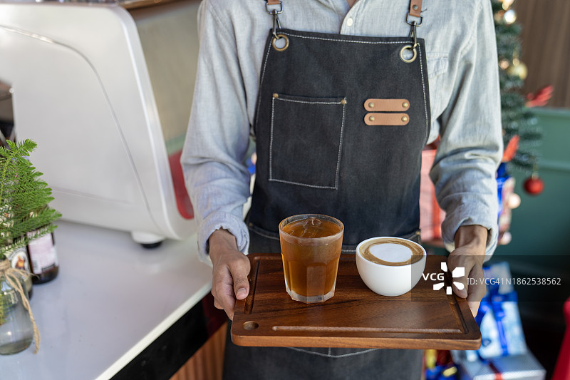年轻的亚洲咖啡师微笑着为顾客服务图片素材