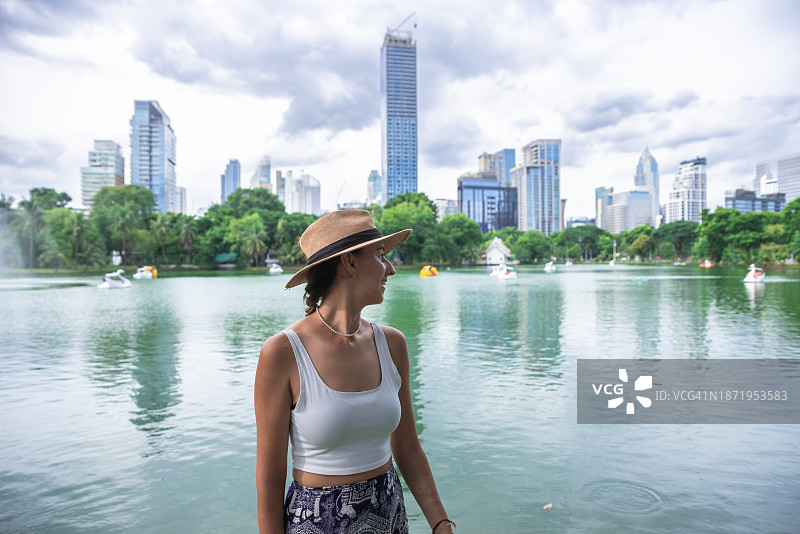 一名女子在曼谷金融中心摆姿势。朗菲尼公园的景色。曼谷,泰国。图片素材