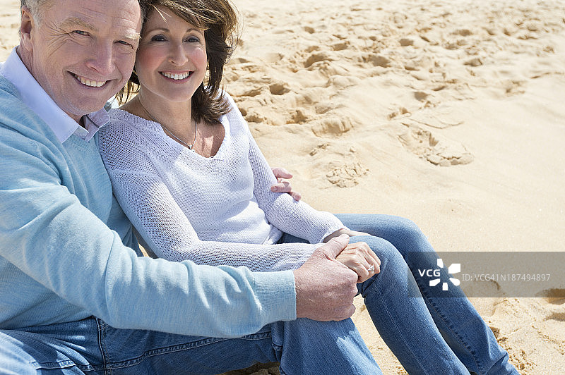一对快乐的成熟夫妇坐在海滩上图片素材