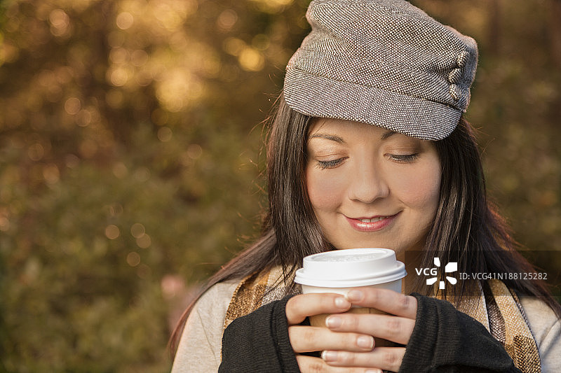 饮料:年轻女子手持热咖啡在秋天。图片素材