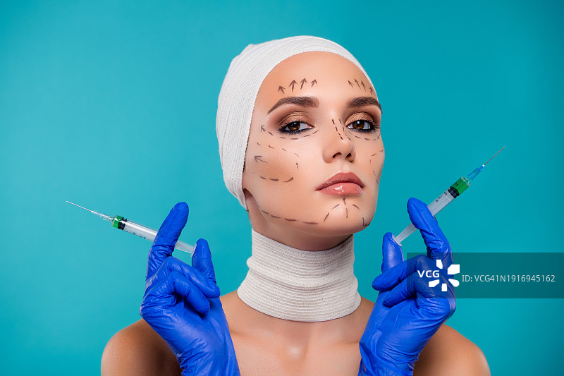 照片的女病人拿着注射器与肉毒杆菌药物整形手术孤立的青色背景图片素材