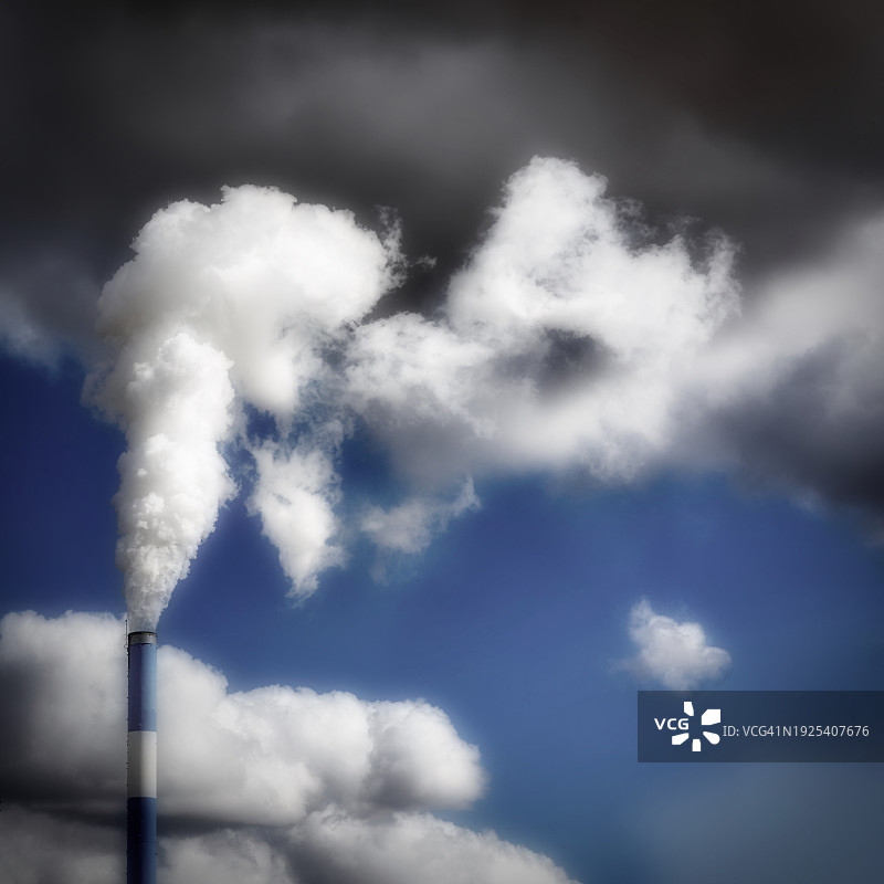 从低角度看烟囱里冒出的烟对着天空，法国昂吉维尔图片素材