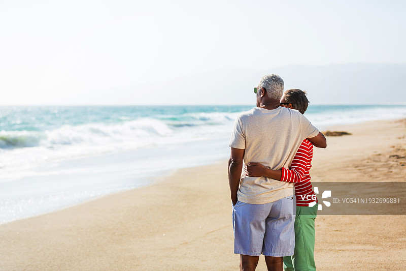 一对年长的非裔美国夫妇在海滩上拥抱图片素材