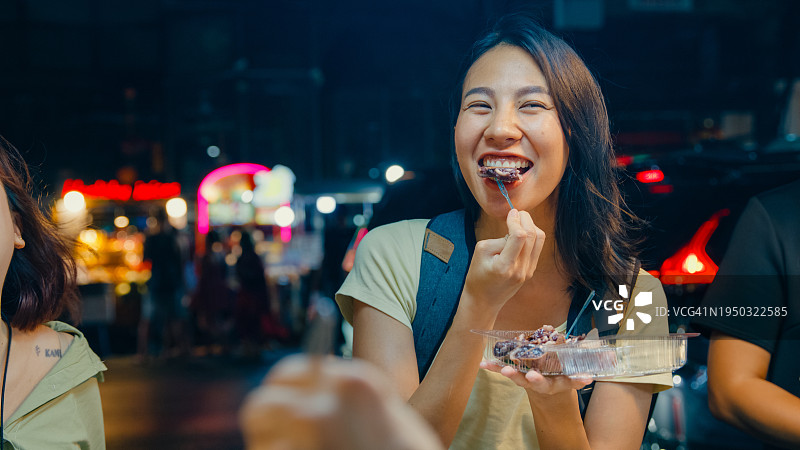 年轻的亚洲女性朋友背包客在泰国曼谷夜市的街头享受街头小吃。假日度假旅行。图片素材