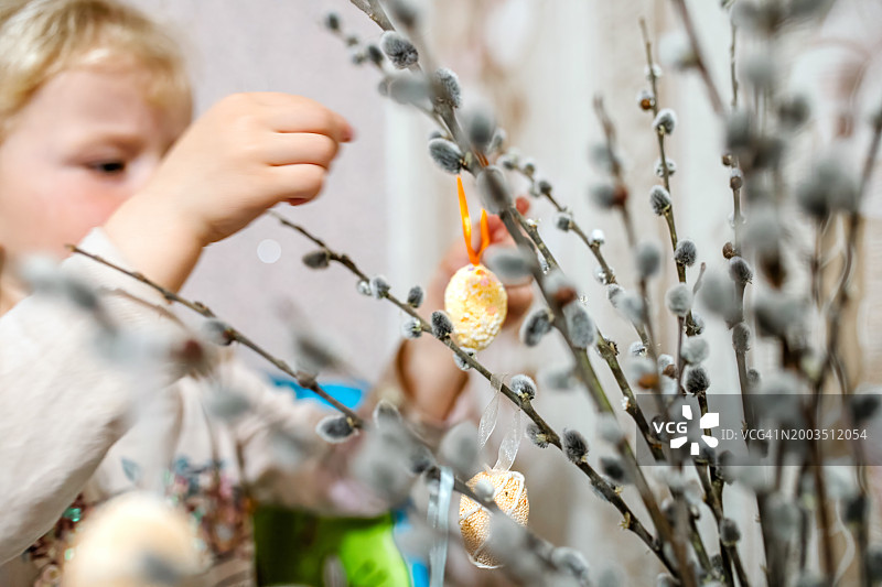 小女孩在家里用柳枝装饰复活节彩蛋图片素材