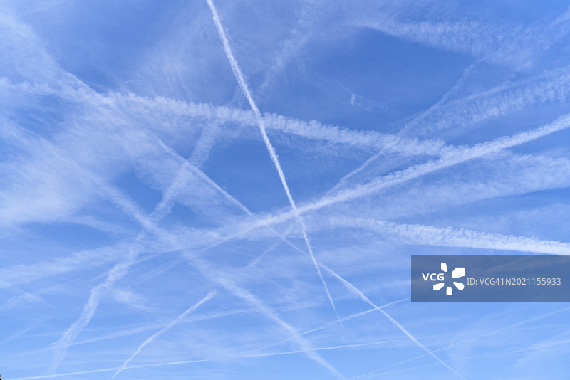 低角度的一组白色的飞机烟雾尾迹在清晰的蓝天背景图片素材