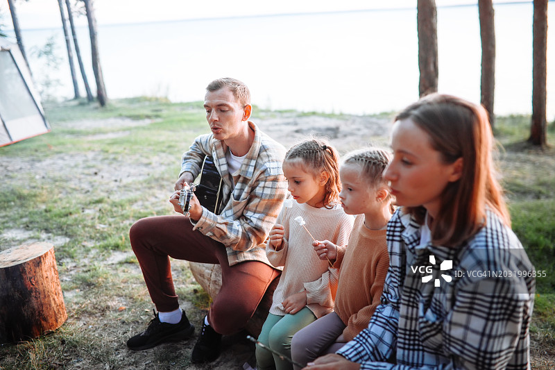 河畔家庭乐趣:孩子们在河边烤棉花糖，伴着吉他小夜曲图片素材