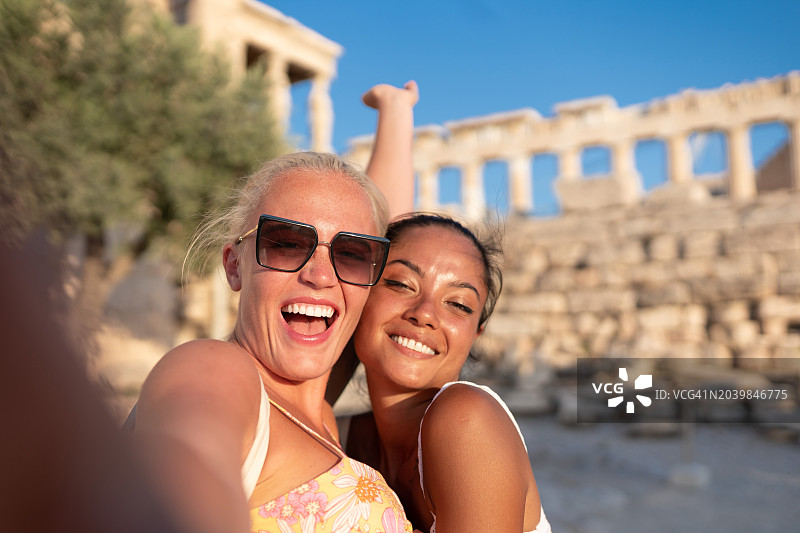 希腊雅典卫城前，多民族女游客微笑着用手机自拍图片素材