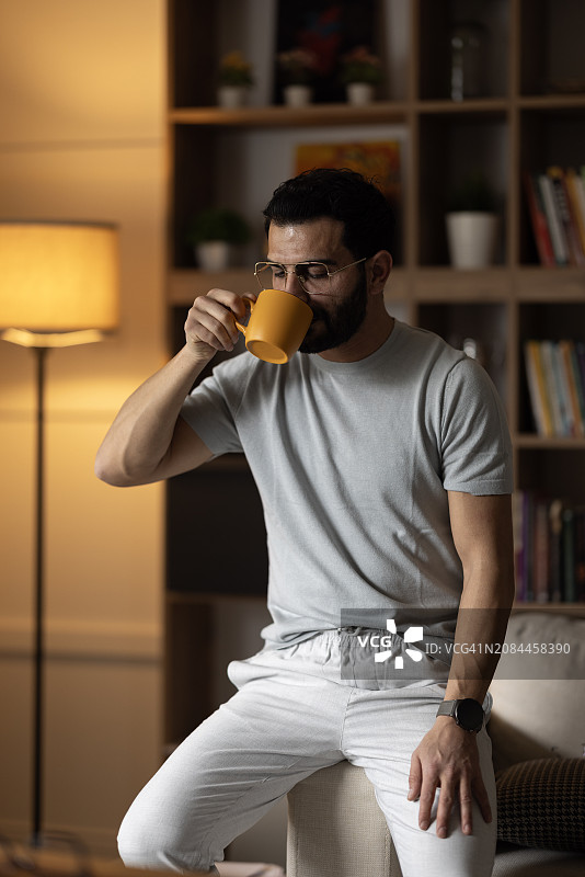 男子端着咖啡杯，望着远方的家图片素材