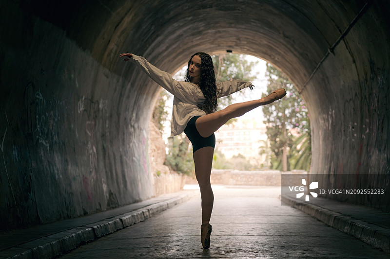 芭蕾舞演员在隧道里摆芭蕾舞姿势。图片素材