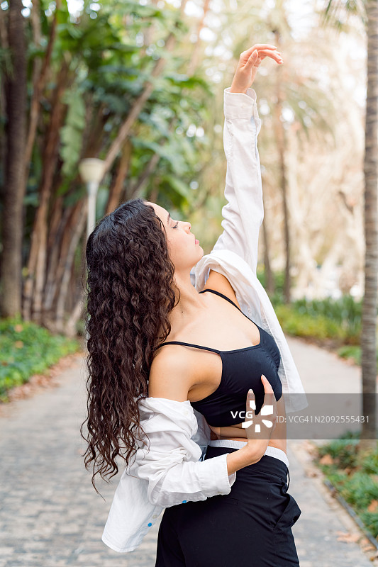 一名芭蕾舞演员在公园里用手臂摆姿势时的背部特写图片素材