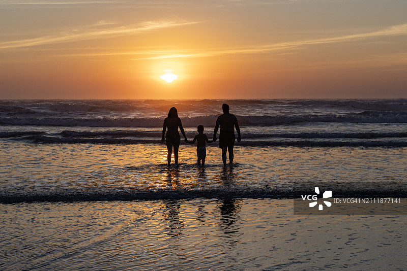 美丽宁静的家庭在日落时走进海洋的浅水图片素材