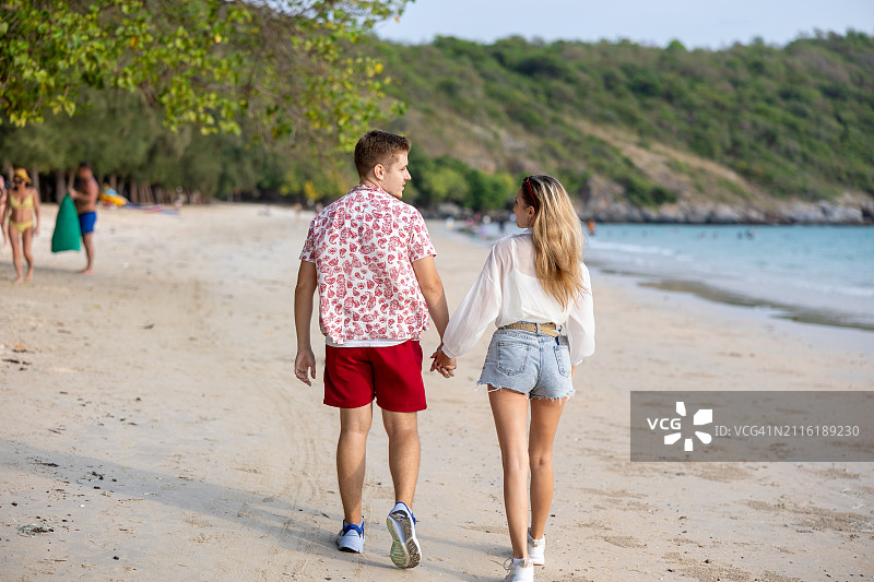 浪漫的日落海滩漫步:高加索夫妇在宁静的海岸线上拥抱爱情和宁静图片素材