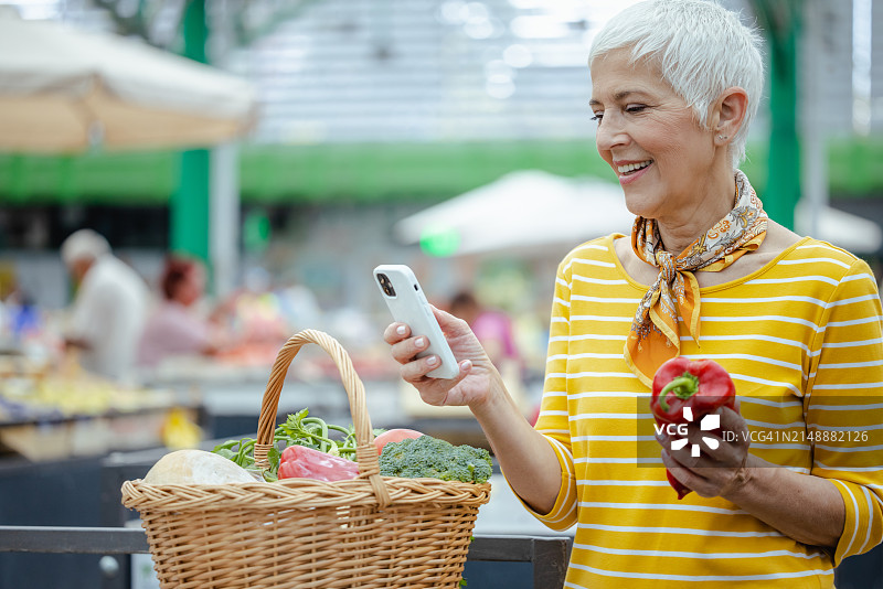 农贸市场上用智能手机的老妇人图片素材