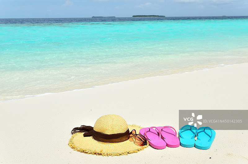 太阳帽太阳镜和彩色凉鞋在沙滩上图片素材