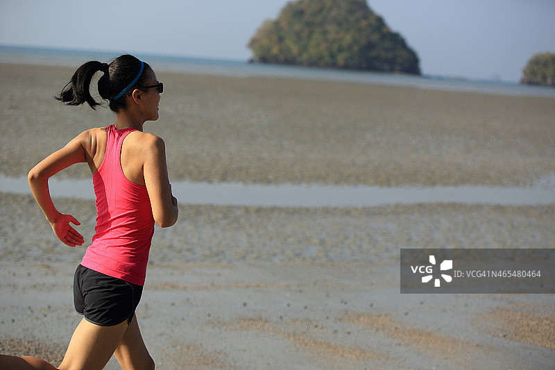 年轻女子在海滩上跑步图片素材
