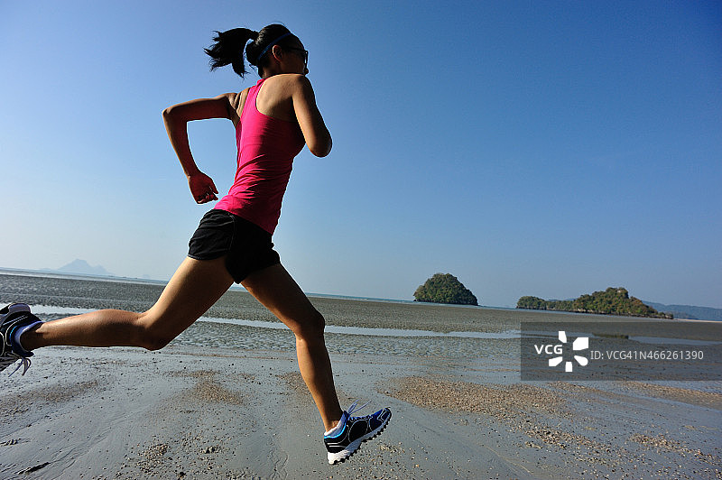 年轻的健身女性在海滩上跑步图片素材