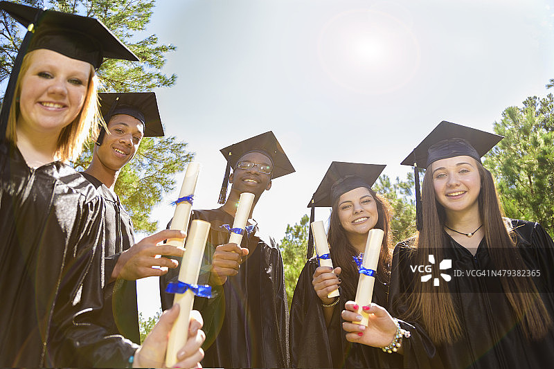 教育背景:毕业时结交不同的朋友。帽,礼服,文凭。图片素材