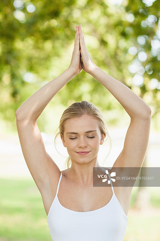 正面的观点，和平的年轻女子做瑜伽在一个公园图片素材